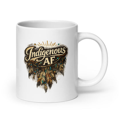 A white ceramic mug with a printed graphic on the front that reads 'Indigenous AF' in stylized lettering above a feather design in brown, gold, and teal, shown on a clean white background.